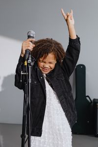 Photo par cottonbro studio Child enjoying a musical performance, holding a microphone and making a rock and roll gesture.