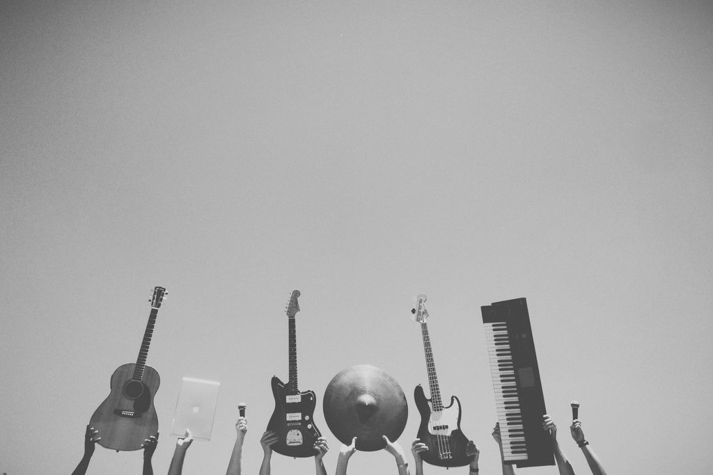 Photo par Snapwire Musical instruments and tech raised in the air against a clear blue sky.