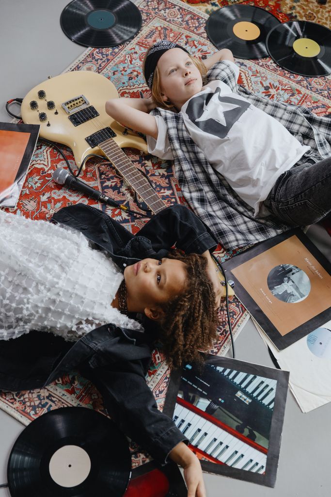Two children enjoy a musical moment among vinyl records and a guitar.